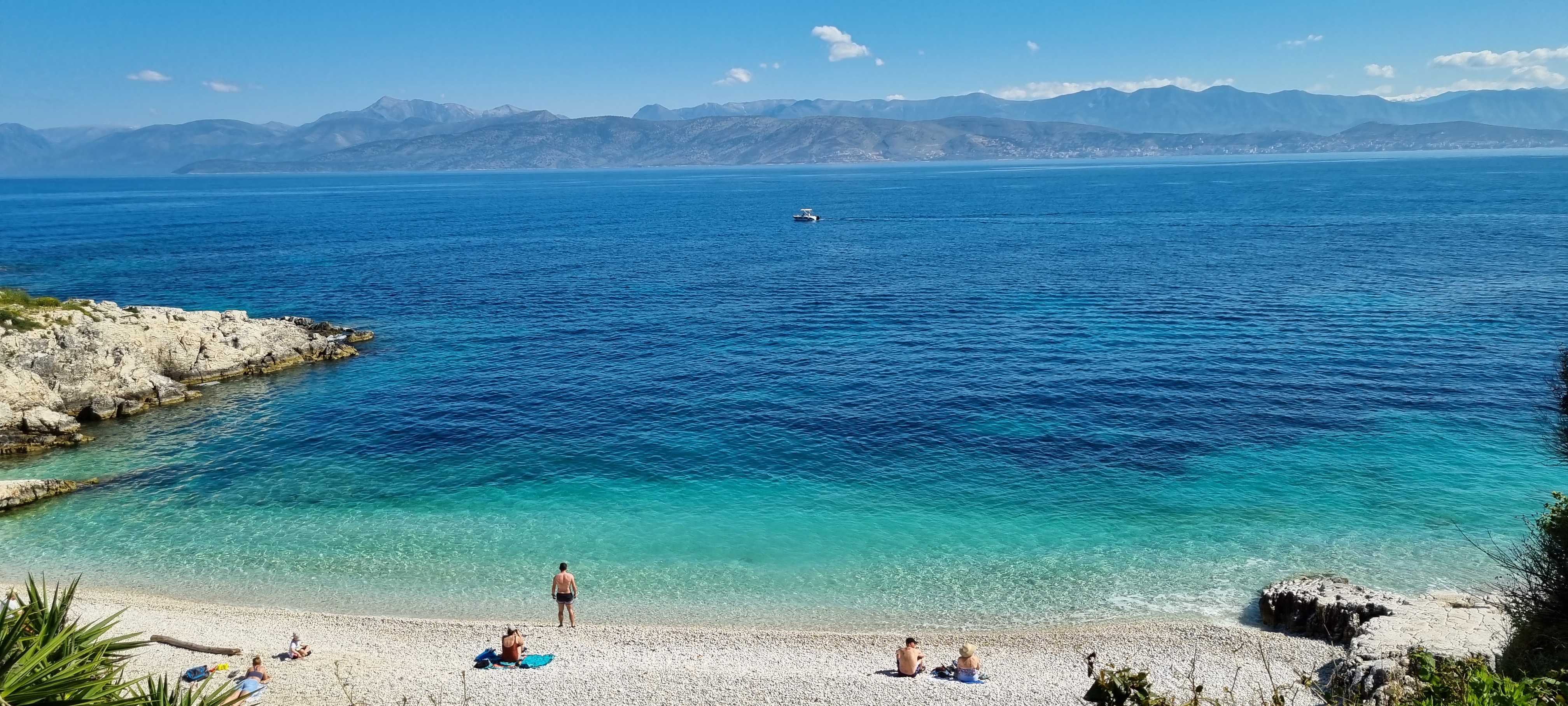 Praia em Corfu com mar azul e pessoas tomando sol